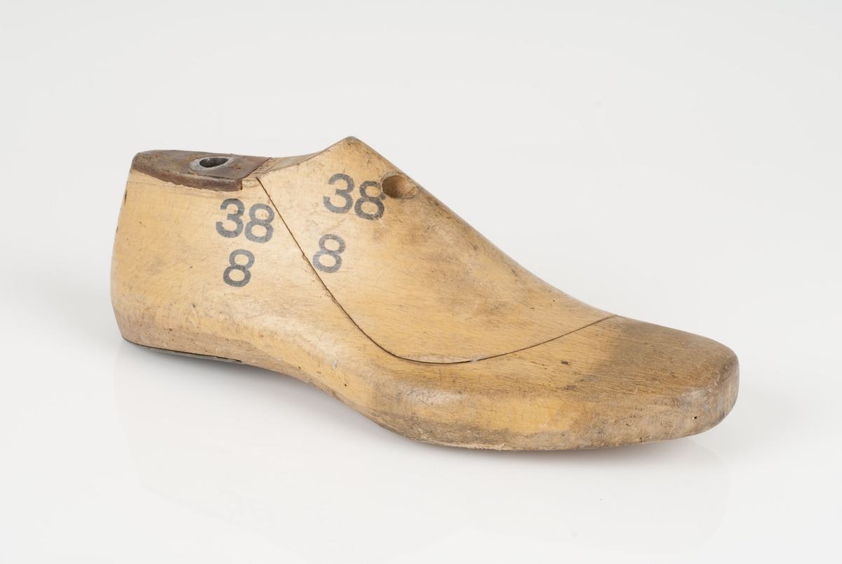 En tremodell i to deler; lest og opplest/overlest (kile).
Høyrefot i skostørrelse 38, og 8 cm i vidde.
Hælstykket i metall.