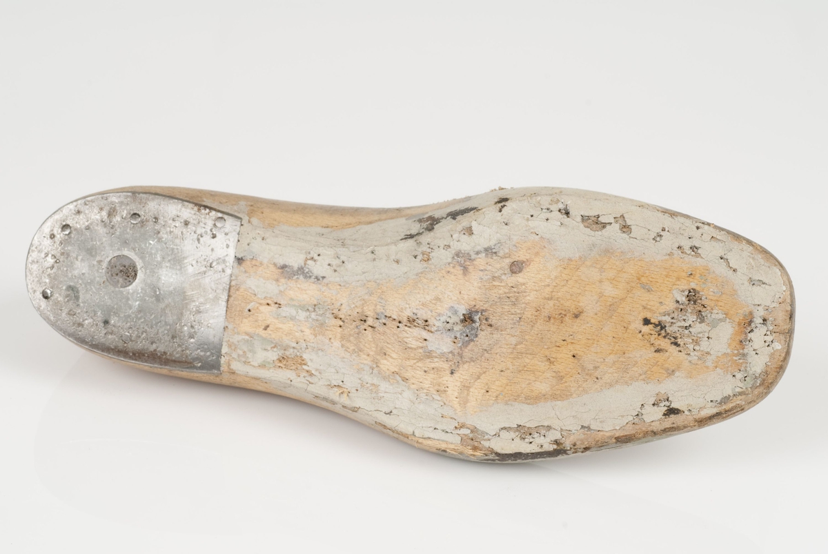 En tremodell i to deler; lest og opplest/overlest (kile).
Venstrefot i skostørrelse 41, og 8 cm i vidde.
Hælstykket i metall.