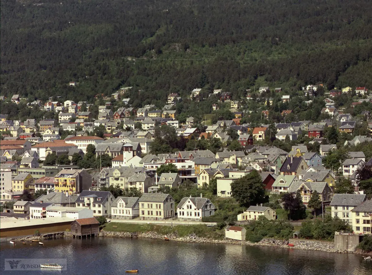 Strandgata, tidl. Grandbakken. Fra venstre Trelastlageret. Bak Regimentsboligen. Mot høyre Presteboligen, så tidl rektorbolig, så sorenskriverboligen. Nedenfor presteboligen ligger Amtmannsbrygga. Øst for sorenskriverboligen ligger Larsens hus med naust. På haugen Edvard Ranviks hus. Videre Harald Isachsens hus (her lå strikkeriet han drev) med hage ned til sjøen og lysthus. Neste hus hørte til Talberg..Strandgt., Grand-området