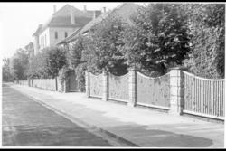 Murvillaer med inngjerdede forhager mot fortau. Tre- og busk