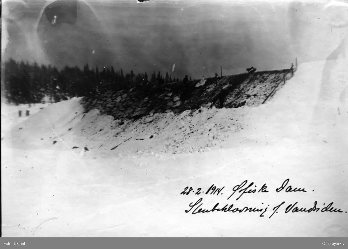 Steinlegging av vannsiden på dammen, arbeidere i virksomhet. (Vinter)