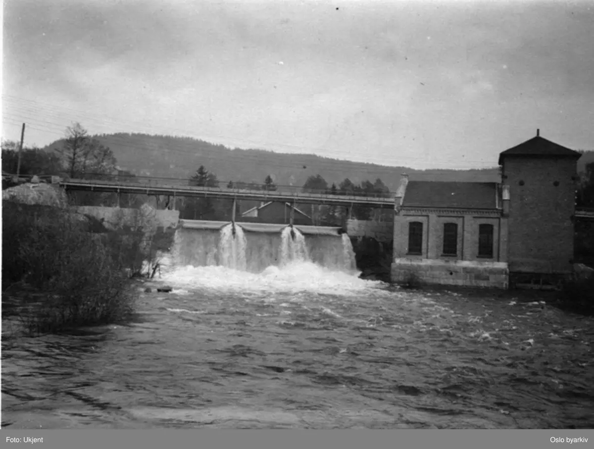 Brekkefossen i Akerselva (flomstor) med kraftstasjon til høyre. Brekke bro.