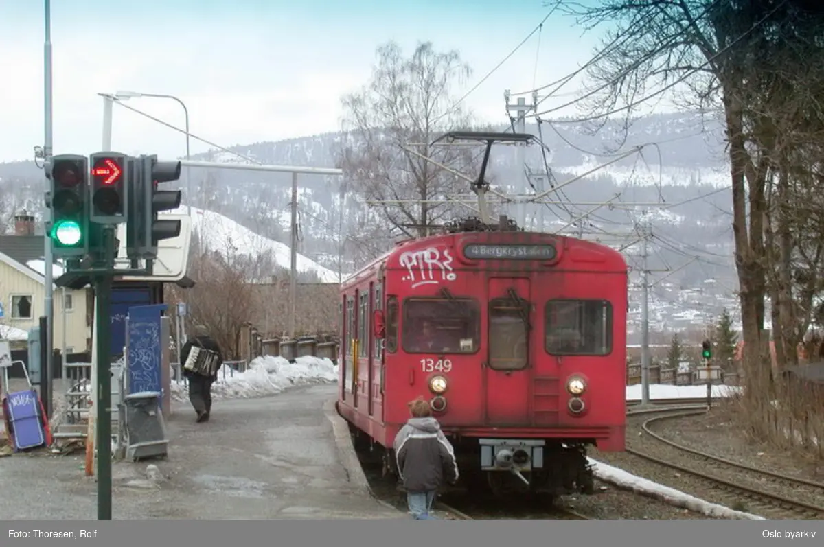 Oslo Sporveier. Kolsåsbanen. T-banevogn, serie T8, delvis tagget vogn 1349 på linje 4 til Bergkrystallen, her ved Gjettum T-banestasjon. Mann med trekkspill. Vinterbilde.