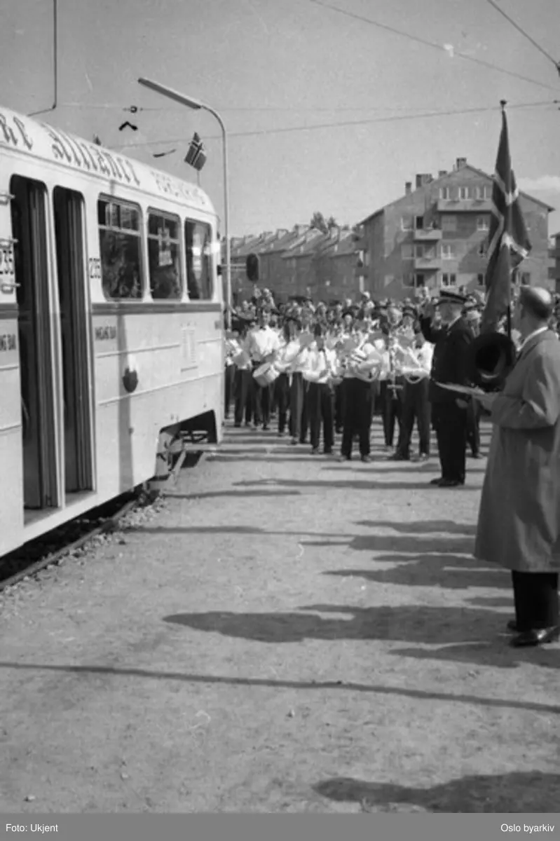 Oslo Sporveier. Trikk motorvogn 235 type Høka MBO linje 4, på Lambertseterbanens åpningsdag, 28. april 1957. Guttemusikken spiller opp, flagg, kontrollør gjør honnør og dignitærer er nok klare til å gå av.