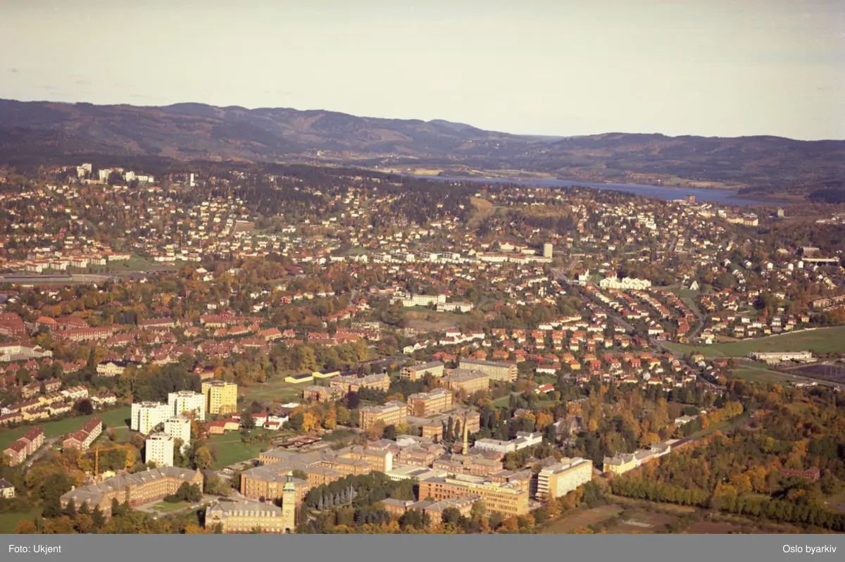 Ullevål sykehus med kirkeveien i front. Høyblokker i Nedre Ullevål. Berg og Tåsen i bakgrunnen. (Flyfoto)