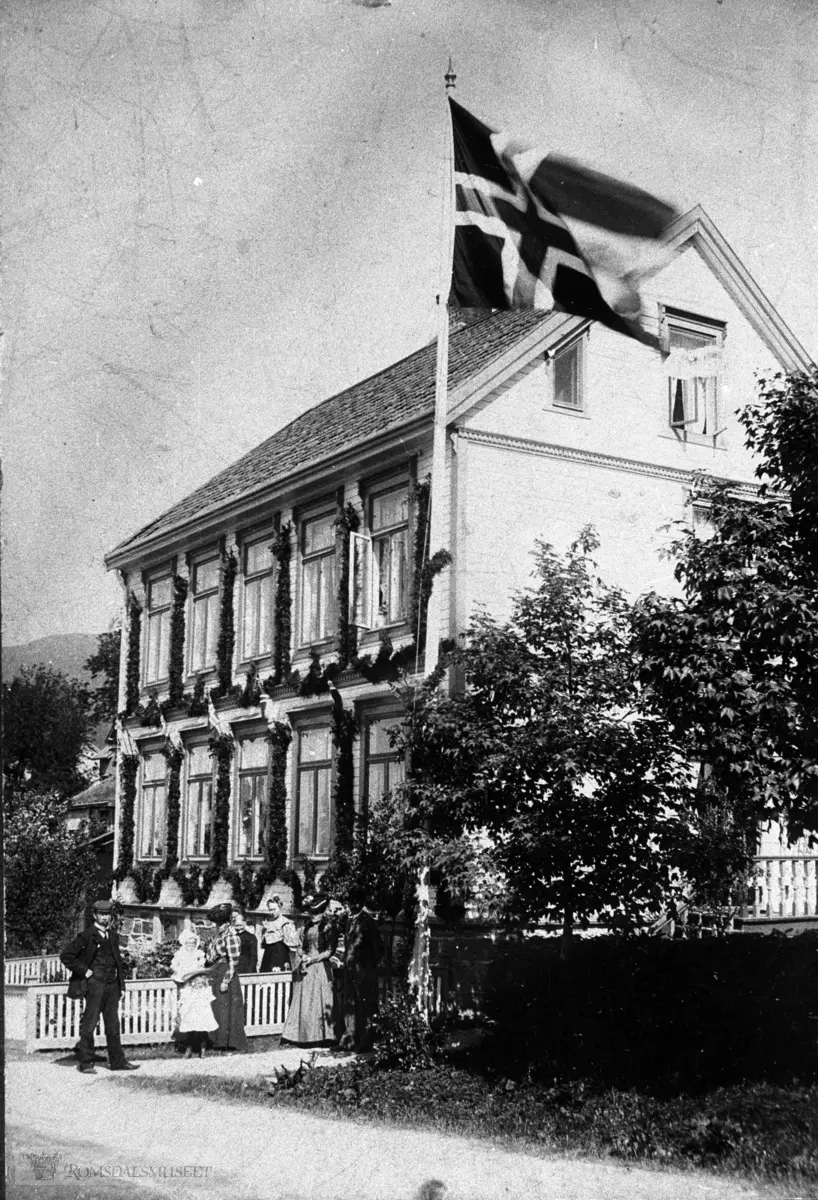 Anton Bø Strande sitt hus..Trebygning i to og en halv etasje. .Flagg og blomster i høve kongebesøket i 1906.