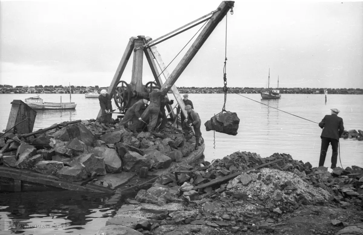 Utfylling med stein under bygging av kai på Støholmen. .Hamna med moloen i bakgrunnen.