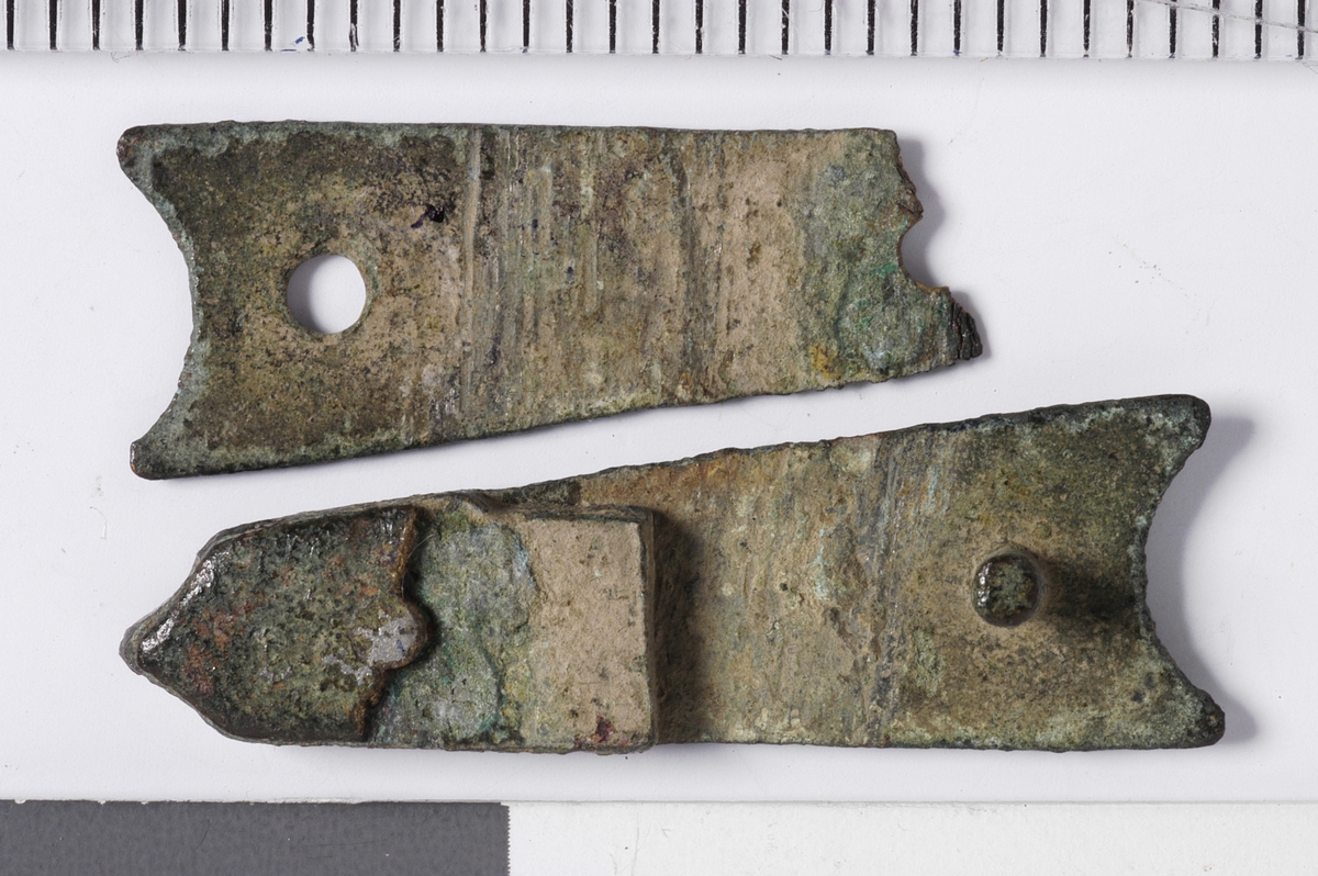 MALV: L. 25, 5  B. 8 MM, BÅNDFORMET BESLAG SOM SMALNER I ENE ENDEN. TO NAGLERSITTER I. RESTER AV LÆRET ANGIR EN TYKKELSE PÅ 1, 5 MM. 