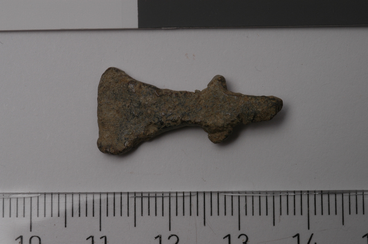 MALV: L. 27  ST. B. 12, 4 MM, HODET ER SYMETRISK OG NOE BREDBLADET.
Øksehode i miniatyr.
