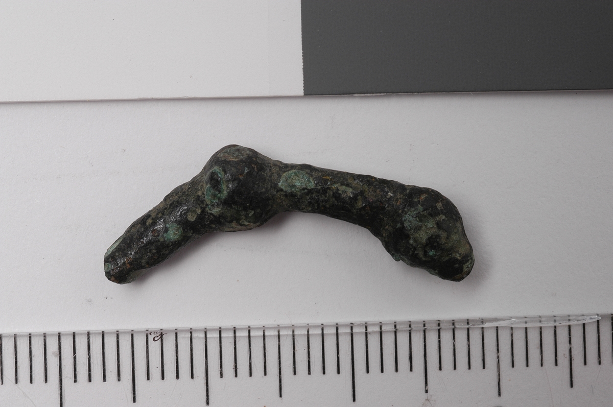 MALV: DIAM. 3 MM, STØPT. DEN ENE ENDEN HAR EN UTFORMING SOM VAGT ANTYDER ET DYREHODE OG ET STYKKE INNENFOR EN KULEFORMET FORTYKKELSE. AVBRUTT I ANDRE ENDEN.