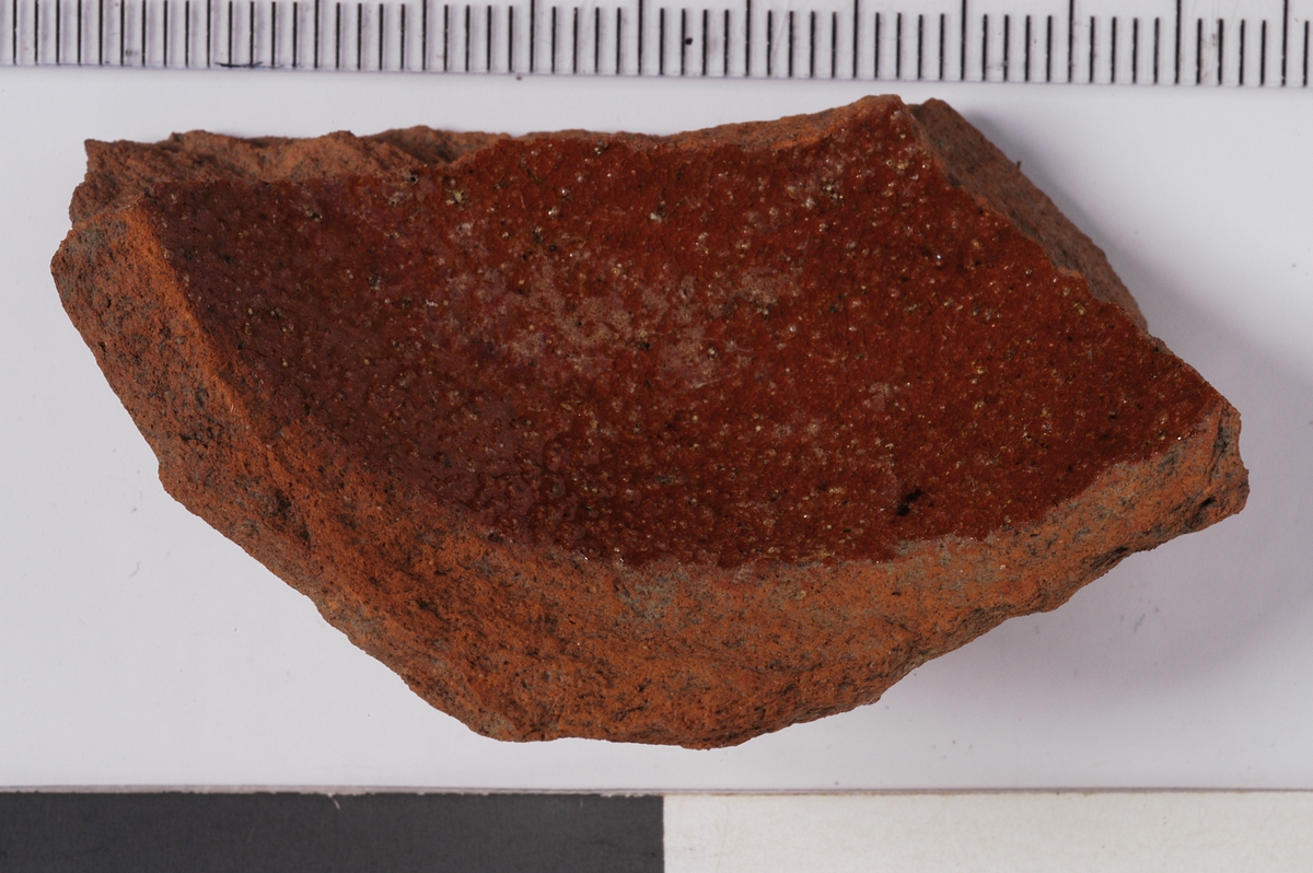 MÅL: ST. L. 54 MM  H. 20 MM, DEL AV RUND STANDFLATE MED NOE AV SIDEN. UTVENDIG UGLASERT, INNVENDIG BRUN SALTGLASUR.