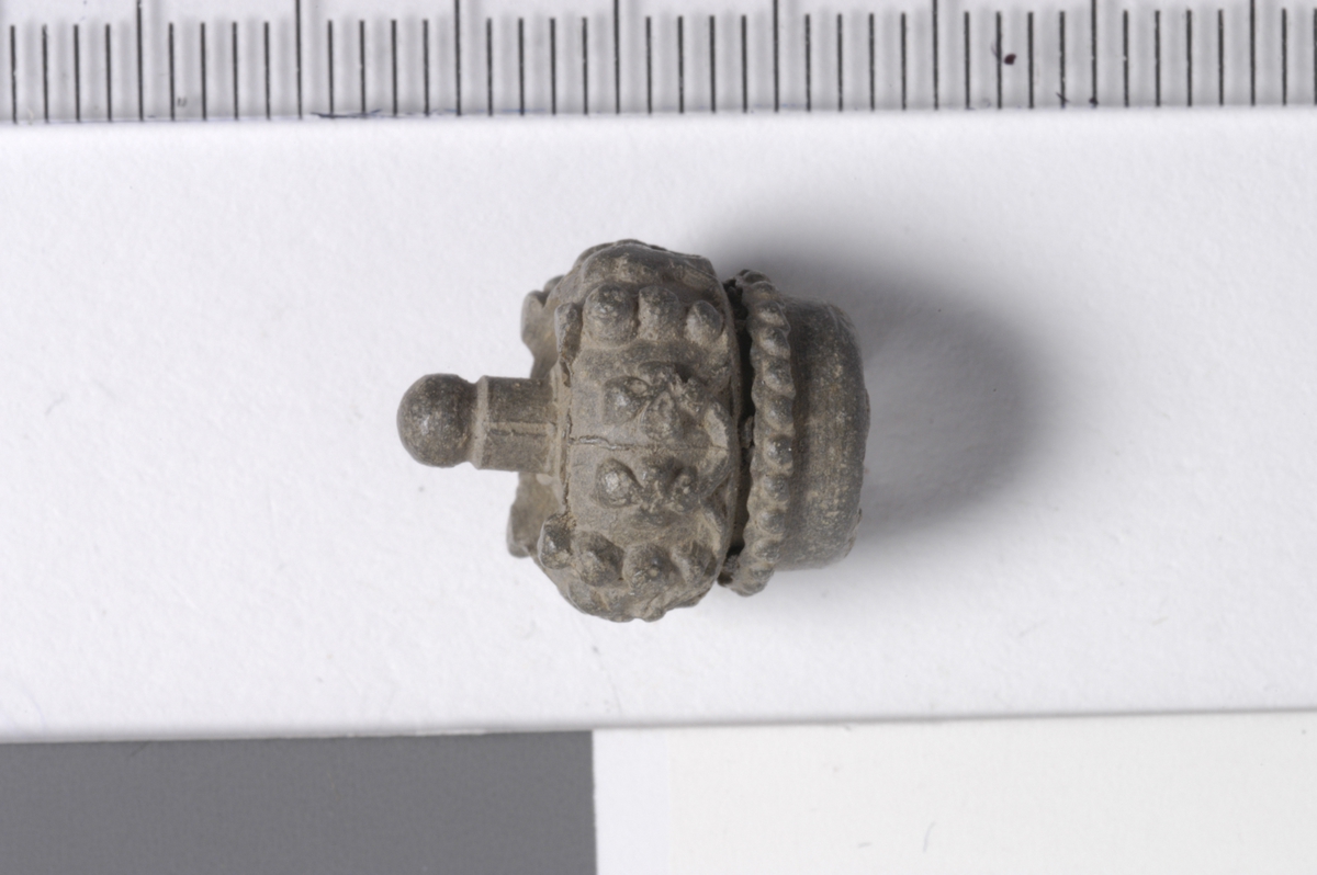 MALV: DIAM. 12, 2 MM, FRAGMENT FORMET SOM EN KRONE - SKRUE SITTE INNVENDIG. Basert på lignende funn (metalldetektorfunn) defineres dette som en kork fra en tannkremtube, tidlig 1900-tall. Stymol(?).