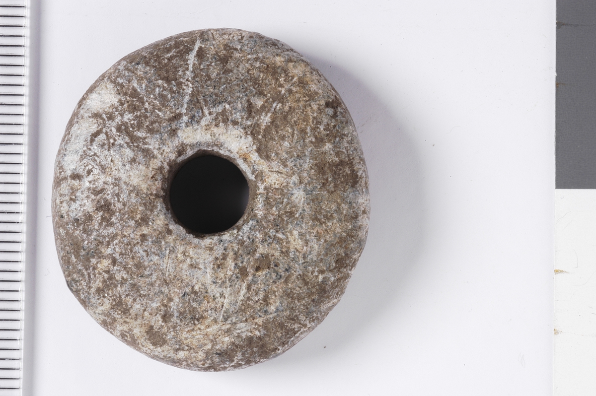 Spinnehjul i stein med flat underside, buede sider og overside.