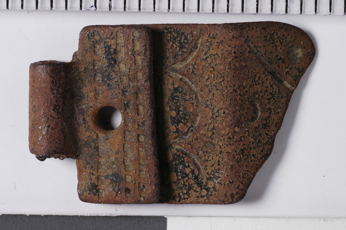 MALV: 19, 2*12 MM, BÅNDFORMET FRAGMENT SOM I ENE ENDEN ER BRETTETDOBBELT. I SELVE BØYEN ER BESLAGET BEVEGELIG. SPOR AV INNSTEMPLETDEKOR. 