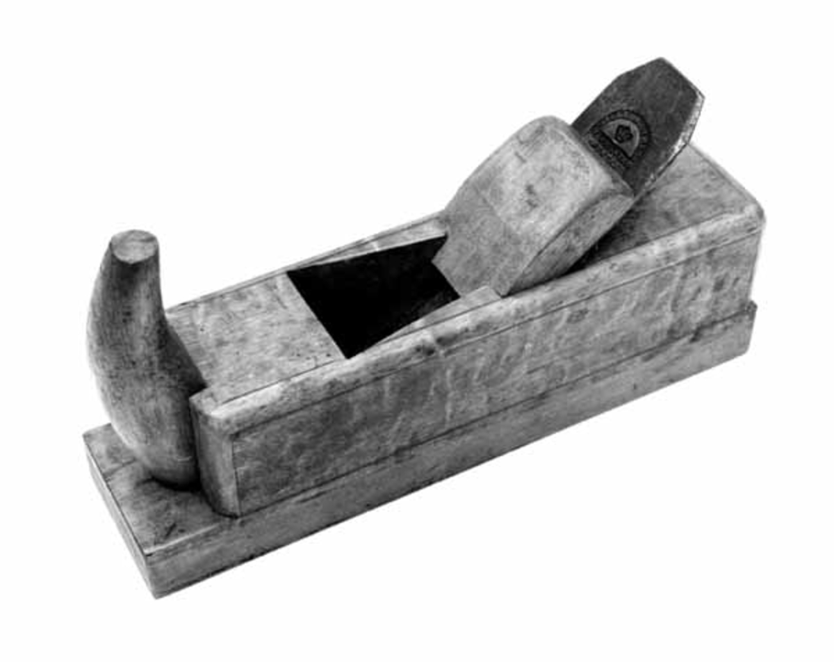 Sletthøvel, altså en høvel som er lagd med sikte på at den skulle brukes til å forme glatte og plane overflater på arbeidsstykker av tre. Høvelen er i hovedsak lagd av flammet bjørkeved, men med ei pålimt såle av et noe hardere treslag. Stokken - høvelkroppen - har ei rektangulær såle som er 24,5 centimeter lang og 6,1 centimeter bred. Høyden på stokken er drøyt 7,1 centimeter. I fronten er det et 2,7 centimeter langt innsnitt 2,5 centimeter over såla. I den rette veggen bak den avsatsen dette innsnittet har skapt er det inngradet og påskrudd et «horn», et vertikalstilt handtak som snekkeren kunne gripe rundt med mellomrommet mellom tommel og pekefinger. Den øvre delen av høvelstokken har avrundete kanter og hjørner. Sponåpningen i høvelsåla - «kjeften» - måler 0,9 X 4,7 centimeter. Over denne åpningen i såla er det et sponhus med loddrett forvegg og en skrå bakvegg, ei «seng» som skulle tjene som anlegg for høveltanna. Denne senga danner en cirka 42 graders vinkel med sålen og det underliggende arbeidsstykket. I den øvre delen av midtaksen på dette skråplanet er det en forsenkning for skruen som forbinder tanna og sponbryteren («klaffen»). Stokken har innrissete kantstriper og er impregnert med et gulbrunt fargestoff. Høveltanna er 18,3 centimeter lang og 4,4 centimeter bred. Den er utstyrt med en sponbryter som er fastskrudd i ei nøkkelhullformet spalte langs tannas midtakse i lengderetningen. Tanna er stemplet «WILLIAM ASH & CO  WARRANTED CAST STEEL» og sponbryteren (klaffen) er stemplet «W. ASH & CO CAST STEEL». Den festes i høvelstokken ved å legge den mot senga og deretter skyve ned en 11,4 centimeter lang og 4,7 centimeter bred trekile med et U-formet innsnitt i den nedre enden mellom sponbryteren og to skråstilte «kjaker» i sponhusets sidevegger.