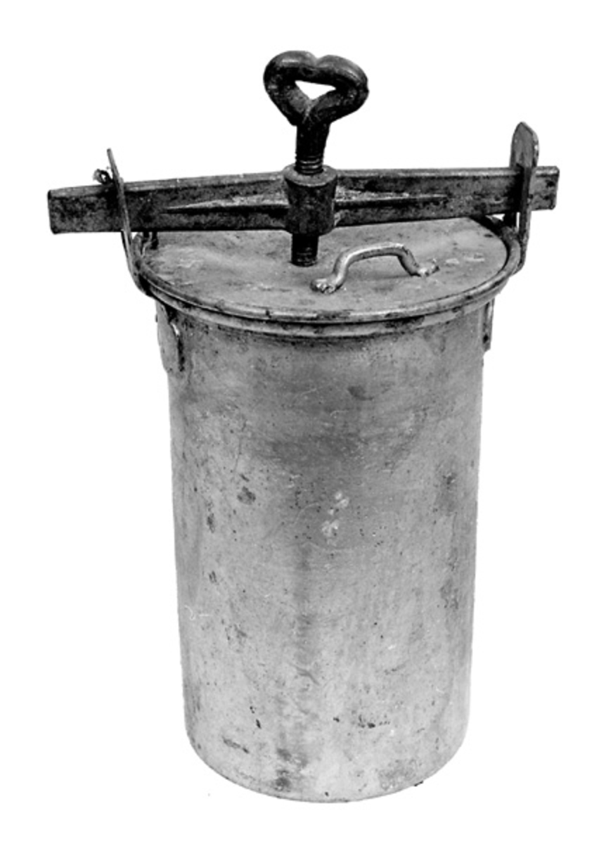 Hermetiseringsbeholderen er laget av fortinnet jern. Den er sylindrisk, 18,5 centimeter høy («ørene» som lokkene festes i er ikke inkludert i dette målet) og har i hovedsak en diameter på 10,4 centimeter. Overkanten er imidlertid utkraget. Her er diameteren 12,6 centimeter. Når beholderen fylles til like oppunder den utkragete overkanten kan den romme drøyt 1,4 liter. Ved overkanten, diametralt plassert i forhold til hverandre, er det påklinket og fastloddet to oppoverrettete «ører» med gjennombrutte, rektangulære hull for feste av lokk og forseglende pakning. Beholderen har to lokk. Det underste har er lagd av forholdsvis tynt blikk og har en diameter på 10,9 centimeter. Midt på denne plata er det en skålformet forsenkning med cirka 30 centimeters diameter. Ytterkantene er noe oppovervendte. Oppå dette lokket legges en pakning, en cirka 2,3 centimeter bred gummiring med en ytre diameter på 11,9 centimeter. Oppå pakningen legges et ytre lokk, lagd av ei 1,9 millimeter tjukk plate med 11,8 centimeters diameter. Også her er den midtre delen noe forsenket. Mot ytterkanten er det påseveiset ei lita handtaksbøyle. Lokkene og pakningen festes ved hjelp av ei 16,5 centimeter lang jernstang der det er plassert en nedoverrettet vingeskrue på midten. Stangas ytterender stikkes inn i hullene i de nevnte ørene øverst på beholderen. Deretter strammes skruen, slik at lokkene og pakningen presses hardt ned mot den utkragete overkanten på beholderen.