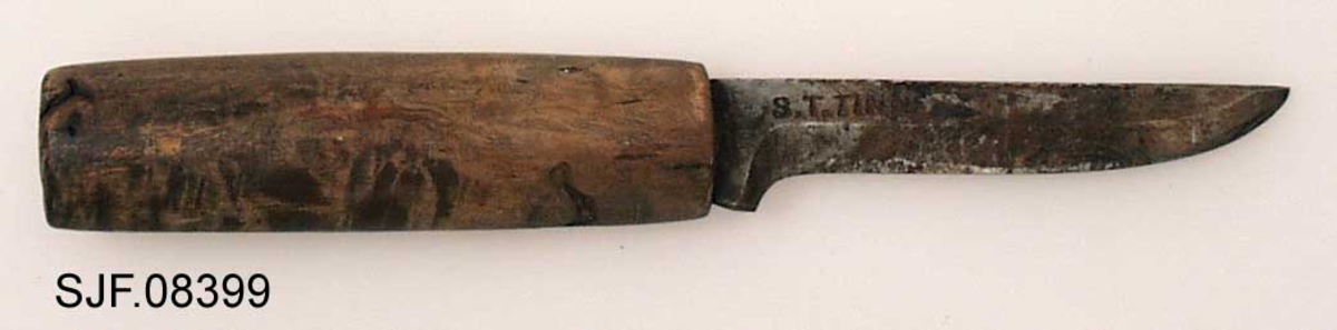 Tollekniv uten slire, lagd av smeden Svein Svimbil (1888-1987) fra Tinn Austbygd i Vest-Telemark. Kniven er 19,5 centimeter lang. Knivbladet utgjør 9,1 centimeter av dette lengdemålet. Bladet er 2,1 centimeter bredt bakerst ved brystningen, men egglinja er slipt såpass mange ganger at bladbredden på midten er bare om lag 1,5 centimeter. Bladtjukkelsen er om lag 4 millimeter ved brystningen, men bladet tynnes gradvis framover mot knivspissen. Bladryggen er forholdsvis rett, riktignok en aning konvekst buet i den fremre enden, der sidekantene er avfasete. Smeden har plassert stempelet sitt - «S.T. TINN» bakerst på det som når kniven holdes i arbeidsstilling er høyre bladside. De nevnte initialene refererer til Svein Tverberg, som var det navnet smeden brukte før han kjøpte småbruket Svimbil.