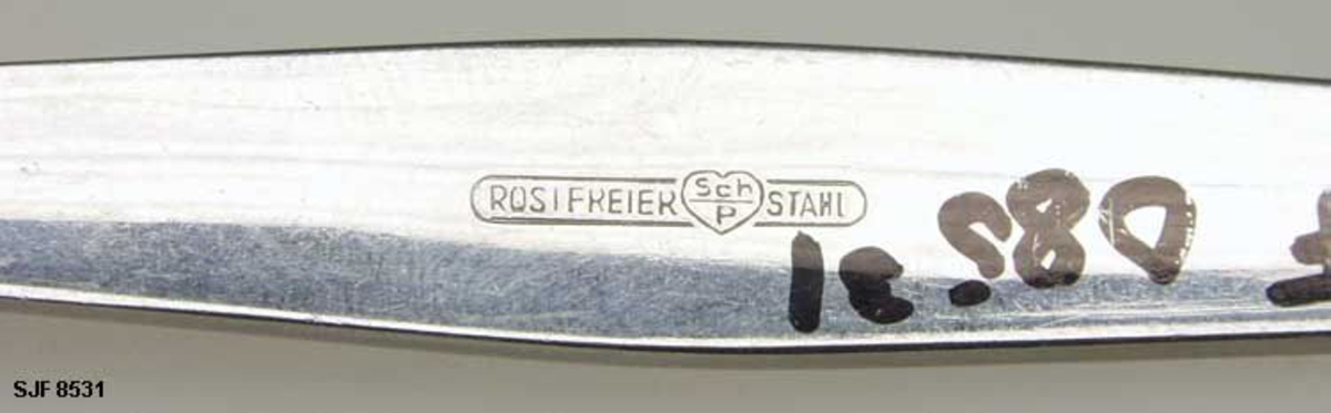 Gaffel, brukt til å holde store matstykker i ro mens de deles i passende, mindre biter med kniv og deretter til å føre matbitene fra tallerken til munn. Gaffelen er lagd av stål, Den er 17,3 centimeter lang. Den fremre enden er 4-tindet og buet i lengderetningen. De ytterste mellomrommene er 4,0 centimeter lange, det midtre 4,4 centimeter. Ved «rota» av tinnene er bredden på gaffelbladet snaut 2,3 centimeter. Denne delen av spiseredskapet er om lag 5,5 centimeter lang. Den fremre enden av skaftet er drøyt 0,7 centimeter bred. Den bakre enden av skaftet er komkavt med største bredde 1,2 centimeter. Undersida av skaftet er stemplet «ROSTFREIER STAHL». Mellom disse to ordene er det en hjertefigur med bokstavene «Sch/P». Denne gaffelen hører sammen med bordkniver av typen SJF.08513.