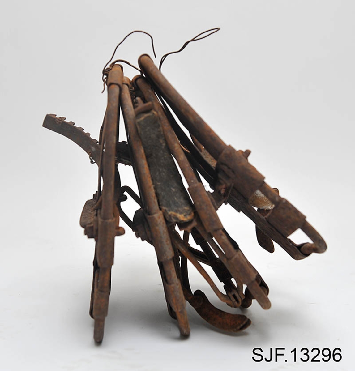 Trugesett for hest, altså fire stykker.  Trugene er lagd av jern.  Rammene er lagd av rør med cirka 1,1 centimeters diameter.  Disse rørene er bøyd i tilnærmet rektangulær form, men med noen avrundete hjørner.  Hver truge er om lag 30 centimeter lang og 24,5 centimeter bred, og har dermed ei bæreflate på drøyt 700 kvadratcentimeter.  Formen holdes stabil ved hjelp av jernband som er bøyd rundt rammerørene og klinket sammen.  To slike band går på tvers av trugene (i bredderetningen) mens det i lengderetningen er lagt band i M- eller W-mønster (avhengig av hvilken veg trugene holdes, M hvis de betraktes skrått bakfra).  De bakerste tverrbandene har kanter som er bøyd oppover, antakelig for å kunne tjene som anlegg for hakene på skogshestens vintersko.  Gjennom de brede tverrbandene noe lengre fram på trugene er det ført jernører med gjennombrutte hull for hengslingslekker for bøyler som ble lagt over hornveggene på hestens framføtter. Den ene bøylehalvdelen har T-formet tverrsnitt med hakk i overkant og lærfôringer på undersida (festet med ståltråd). Ei truge mangler slik fôring, de andre er stive og sprø etter mange års tørk uten tilførsel av nye fettstoffer. Den andre halvdelen av bøylemekanismen består av en lang, buet kjettinglekk med ei dreibar klype med ei gjennomgående nagle like bak hengslingspunktet. Denne nagla føres ned i ett av hakkene på ryggen av den andre bøylehalvdelen, hvoretter endeleddet presses ned. Dermed låses truga godt til foten på hesten. Under tverrbandene bøylene er festet i er det montert jernstag med T-formet tverrsnitt på tvers av trugenes lengderetning. Disse komponentene skulle antakelig redusere faren for at trugene skled på vinterføre. De nevnte tverrstagene er for øvrig festet med kvadratiske muttere på endetappene av «jernørene» som bøylene på oversida av trugene er hengslet til.  På jernet kan vi se spor av oransje lakk, men fargestoffet er i ferd med å bli fortrengt av gravrust. Trugetypen later til å være en serieprodusert artikkel. De brede tverrbandene på to av trugene er merket «ØR» i prikket utførelse. Trugesettet ble levert til museet sammenbuntet med en ståltråd, antakelig slik de har vært oppbevart siden sist de var i bruk.  Ifølge siste eier, Magne Ottershagen fra Styggberget i Elverum, skal dette ha vært vinteren 1953-54.

I Sverige kalles denne trugetypen «norsktrampa», hvilket vel indikerer at det må ha vært en norsk produsent som har eksportert slike truger til nabolandet.