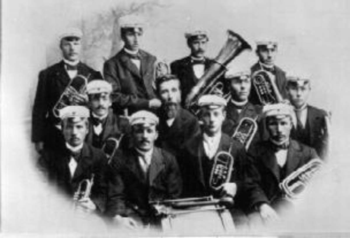 Musikkorps med messingblåsere og trommer. Nes Musikkforening, Nes, Hedmark. Første rad fra venstre er Gustav Thorud, Torger Gaalaas, Ole Lie, Ole j. Huuse. Andre rad fra venstre er Anders Gaalaas, dirigent O.G. Hansen, Bernhard Nyhus, Morten Hansen (sønn av dirigenten). Tredje rad fra venstre er Daniel Lyserud, Even Hovie, Arnt Pedersen, ukjent.