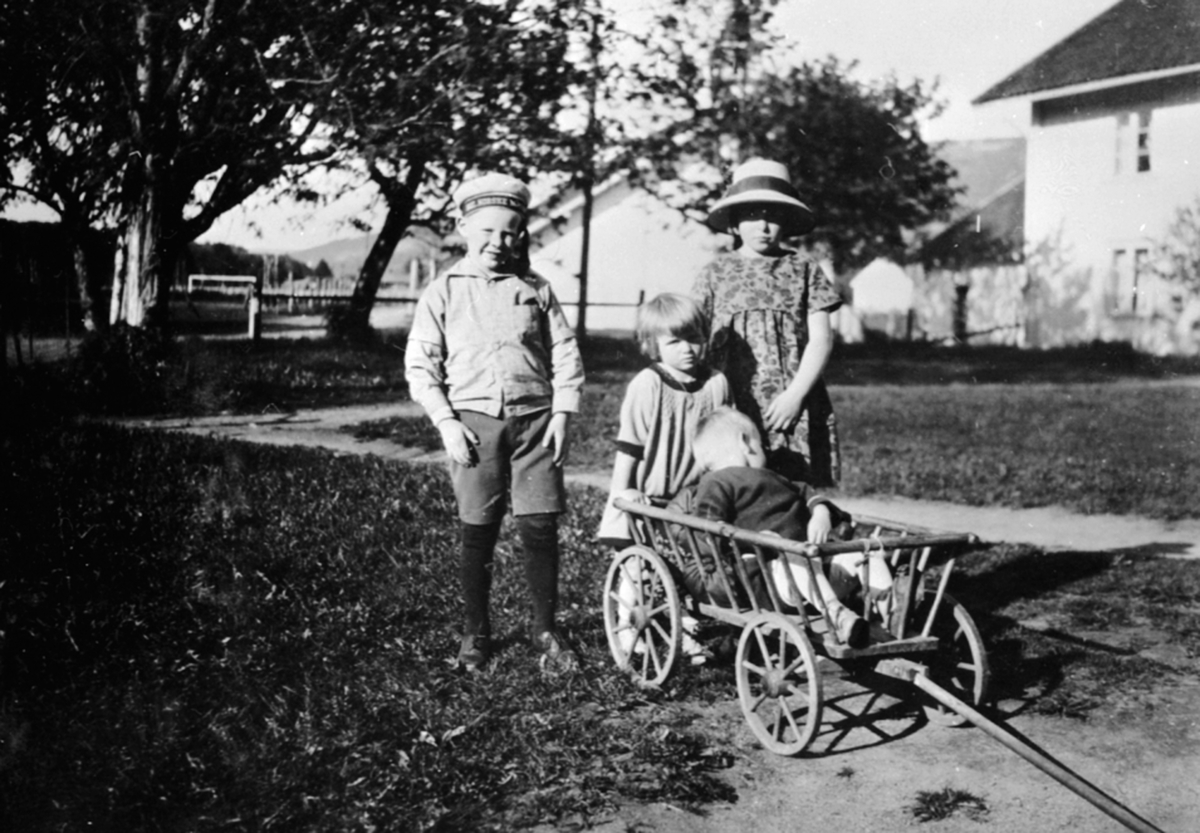 Fire barn i lek med vogn. Hans, Vesla, Margrethe Løken, Karl Alf Løken på Granerud gård, Brumunddal.