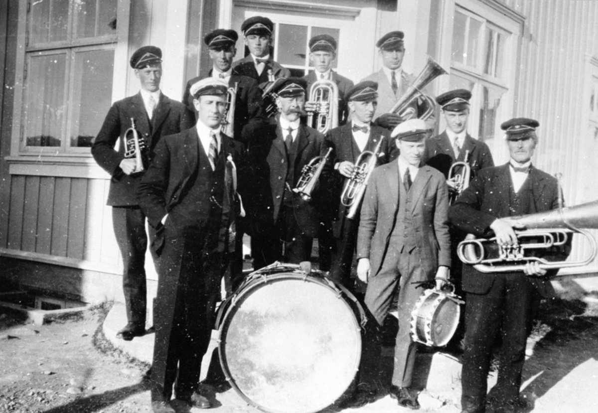 Brumunddal Musikkforening. Foran venstre er Johannes Sørlien, Fredrik Græsby, Sigurd Evensen, Nils Johansen Hegre. I midten er Hans Bakken, Johan Røhne. Bak er Haakon Græsby, Hans Stordahl, Per Hangenholen, Hans Berger, Martinus Larsen, 17. mai, posthustrappa, Brumunddal.