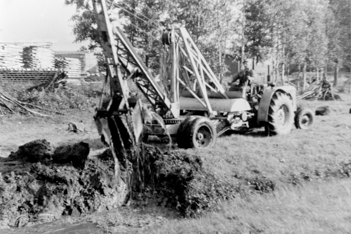 Traktor med gravemaskin, lastemaskin. Demonstrasjon for bruksberettige i Ringsaker Almenning. Graving i torvmyr, grøfting.