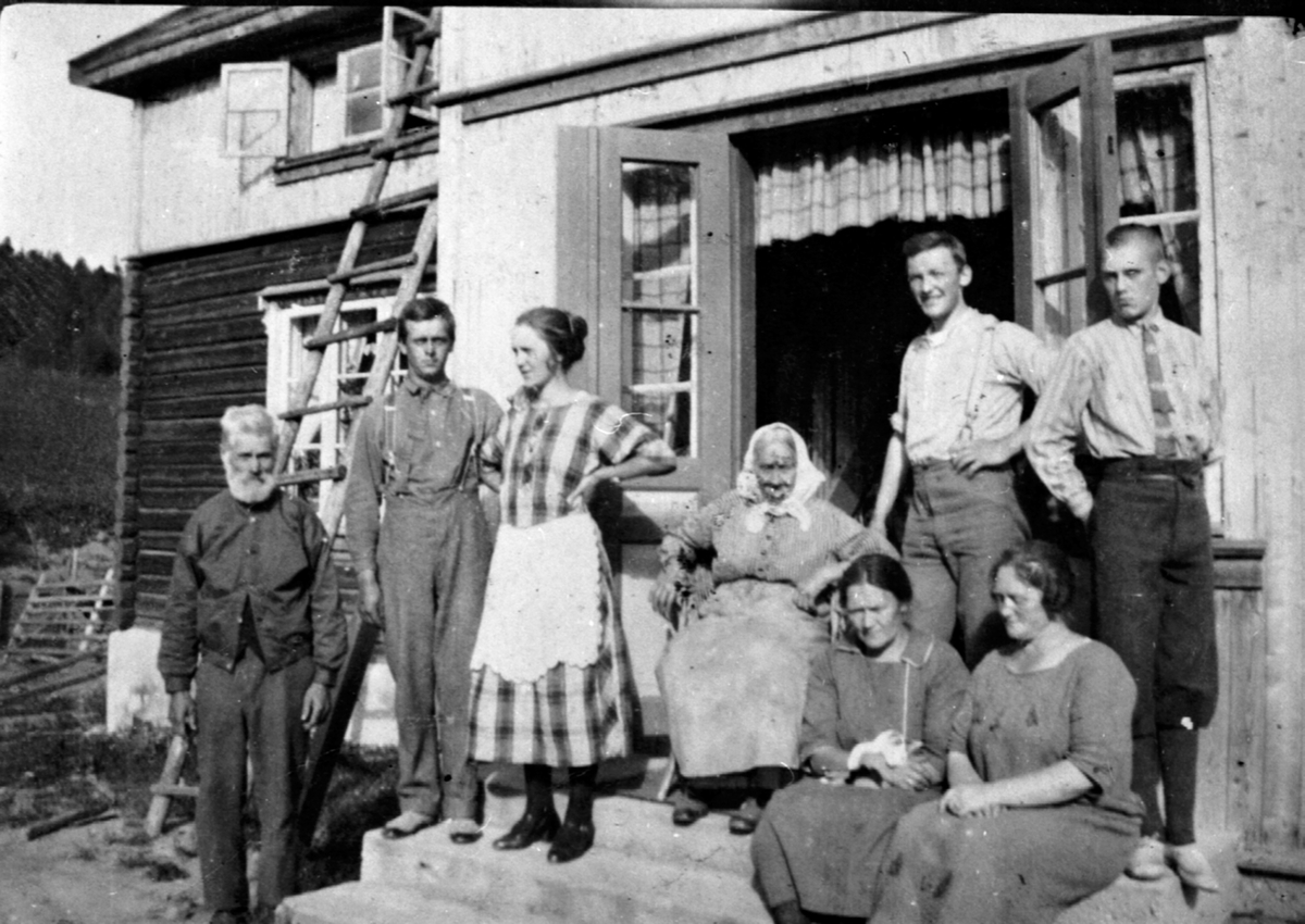 Familien Sandbæk ute foran hovedbygningen på Raknerud nordre, Helgøya. Fra venstre er Retinius Raknerud (1853-1925), Bjarne Olsen Sandbæk (1902-1979), Alvhild Raknerud f.1905, Anne Marie Raknerud (1843-1932), 2 slektninger. Sittende foran er Magda (1884-1953), Emma.