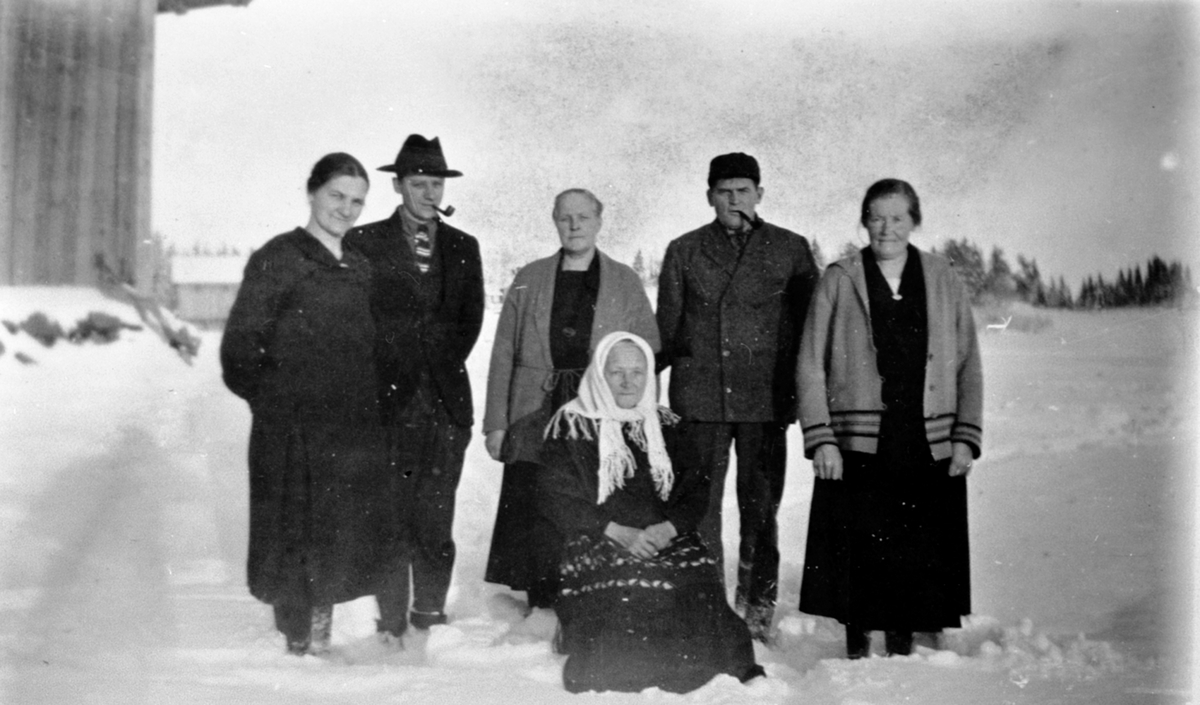 Gruppe voksne utendørs, vinter. Jenny Fjellheim, Simen Fjellheim, Anna Løvli, Sigurd Haugerstuen, Julie Thorstad, sittende er Kari Fjellheim, Brøttum, Ringsaker.