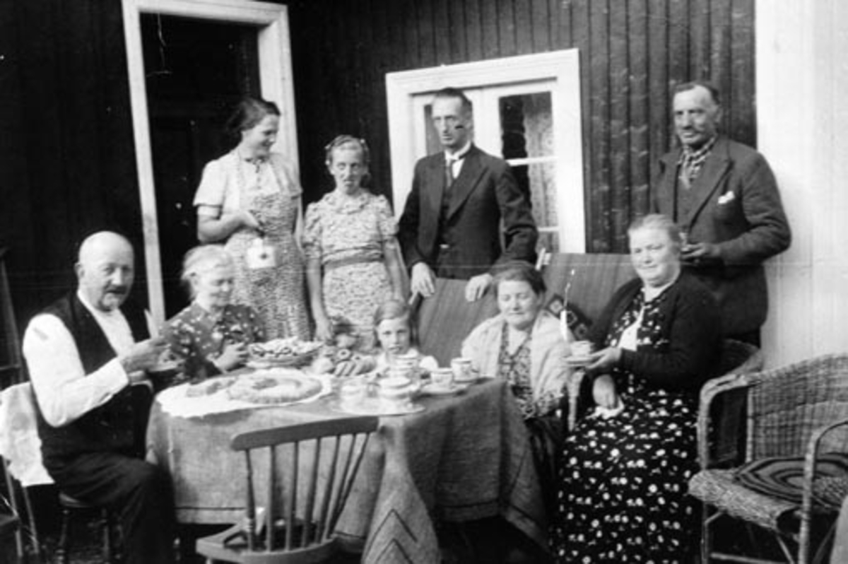 Kaffeservering utendørs, Myrheim, Nes, Hedmark. Fra venstre er baker Lie Hamar, Mina Lie,  damen med kaffe kjelen, er hushjelp Rut Haldis Mangset,  ukjent, Østby, Anders Myhre, Emma Myhre, resten ukjent.