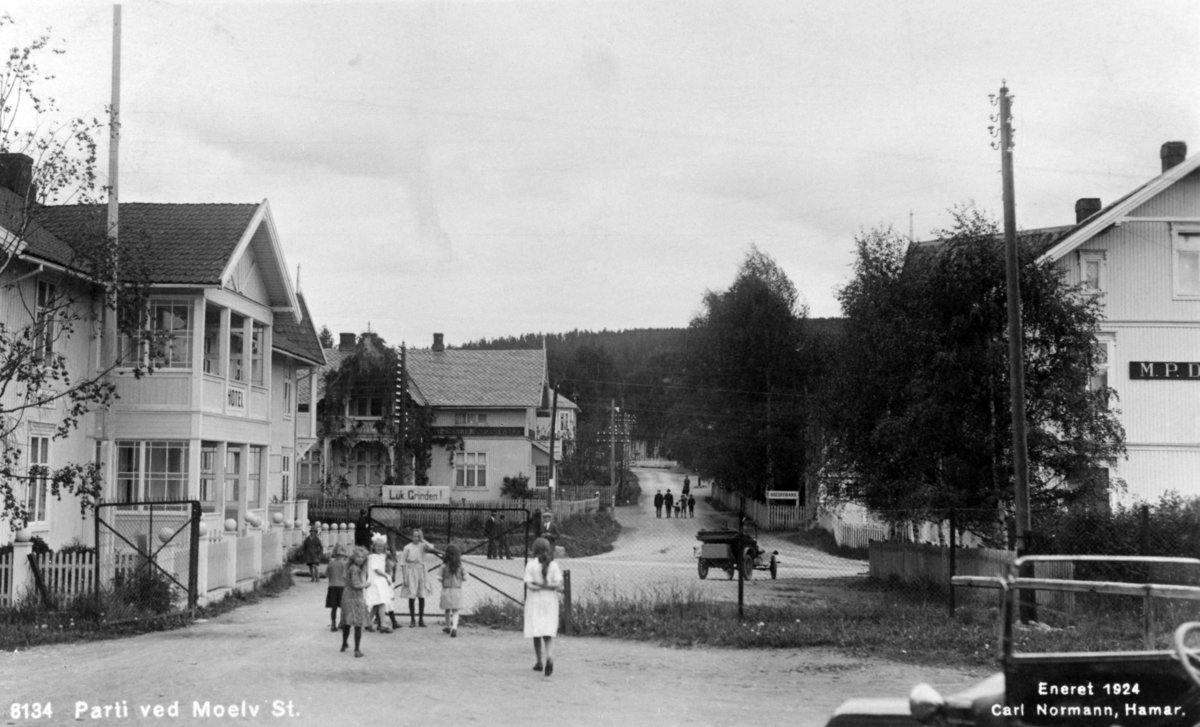 Postkort, Moelv sentrum, sett fra stasjonen mot Åsmarkvegen, til venstre er Moelven hotell, Ringsaker Sparebank, M.P.Dobloug.