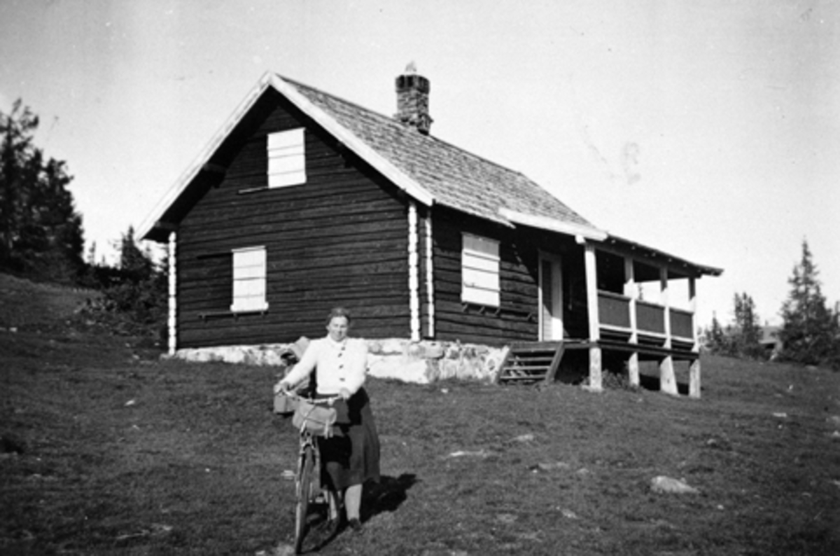 Eksteriør, hytte til Pinnerud gård, Furnes. Ligger på Øyungen, Ringsakerfjellet. Damen med sykkel er Regine Nilsen.