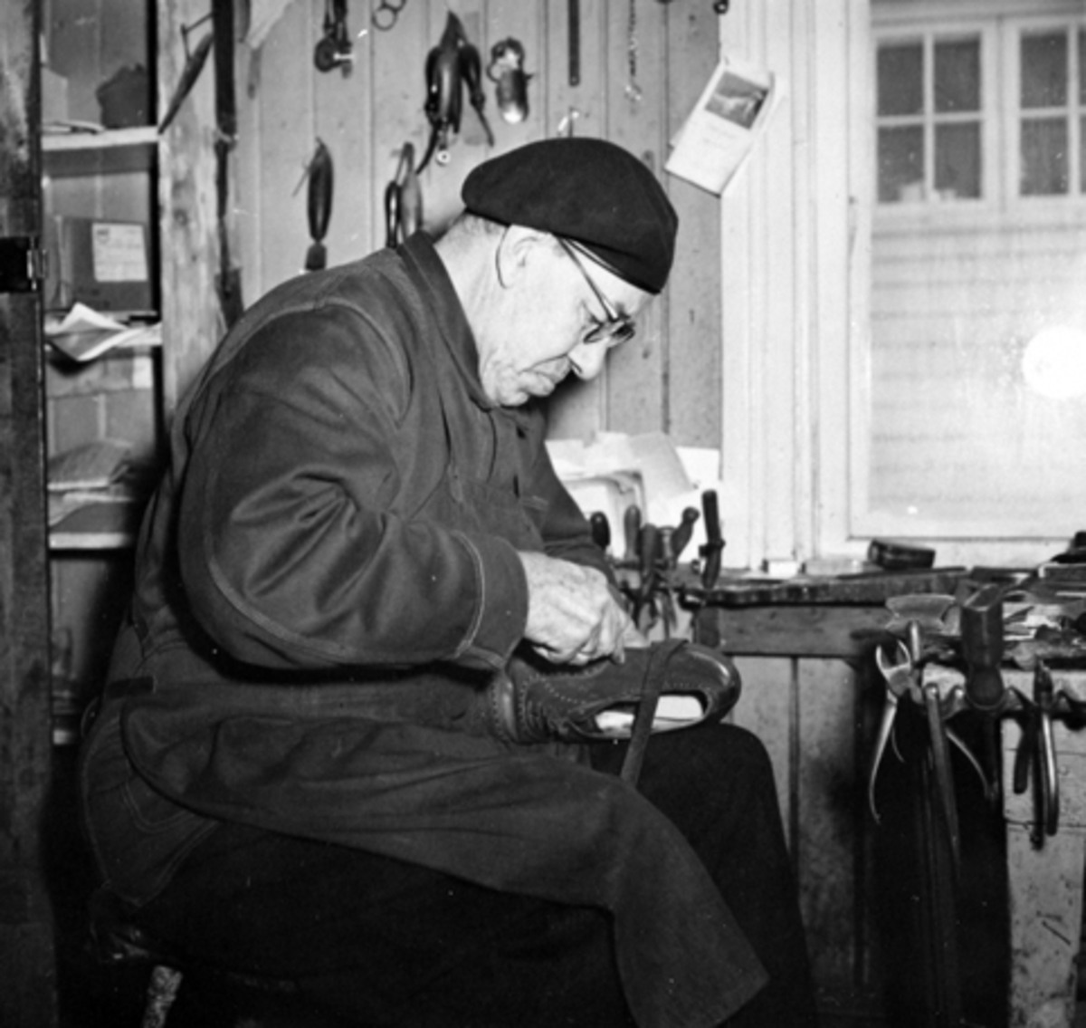 Interiør, skomakerverksted, skomaker Aksel Ludvig Andersen (1887-1966) reparerer sko. Heimdal, Gamlegata 12, Brumunddal.