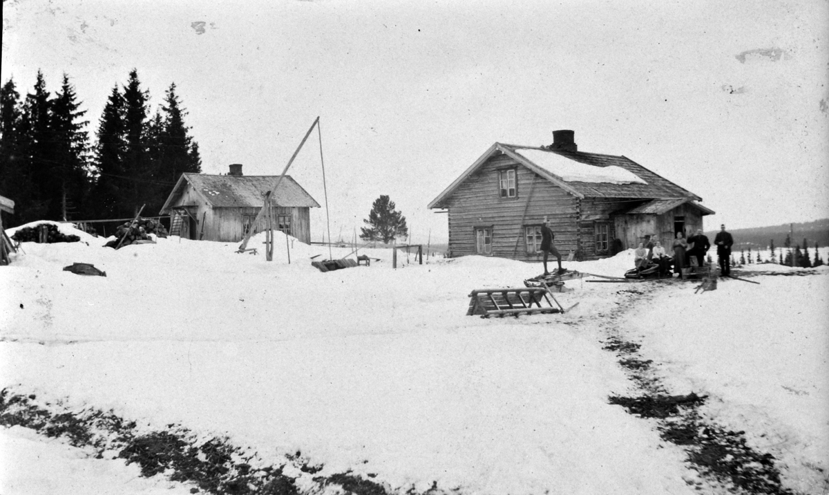 Eksteriør, vippebrønn, Mesnabakken, Mesnalia, Ringsaker. Fra venstre er Mons Bratberg, ukjent, Olga Aaseth, Syverine Aaseth, Johan Aaseth, Trygve Aaseth. Før 1920.