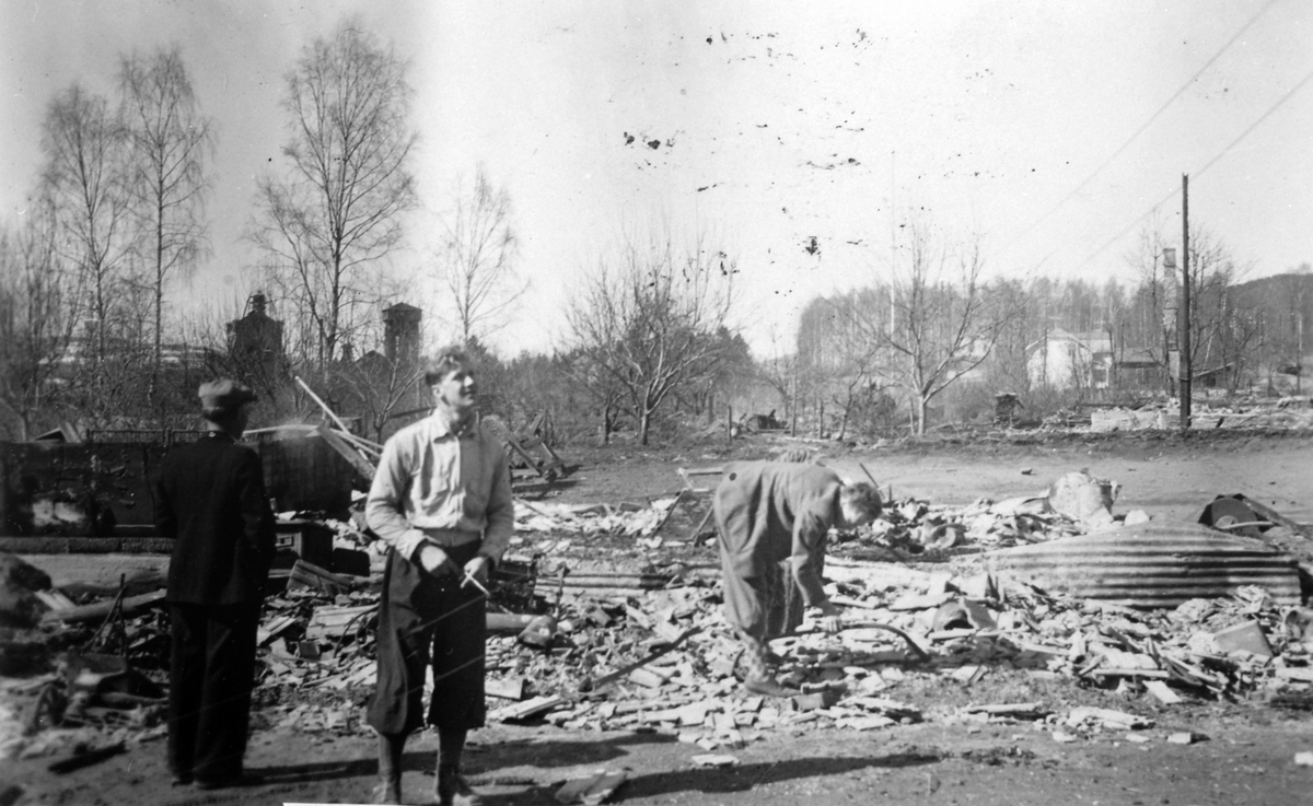 Ringsaker, Moelv, 2. verdenskrig, juni 1940, okkupasjon, krigshandlinger, brannruiner, ved Kilde skole, i forgrunnen ( i dag) Storgata 48 (huset til Severine Larsen), lengst unna ruinene/pipa til huset til kjøpmann K. M. Haugen. I bakgrunnen Ahlsens hus, og anleggene og disponentboligen på Moelven Cellulosefabrikk,