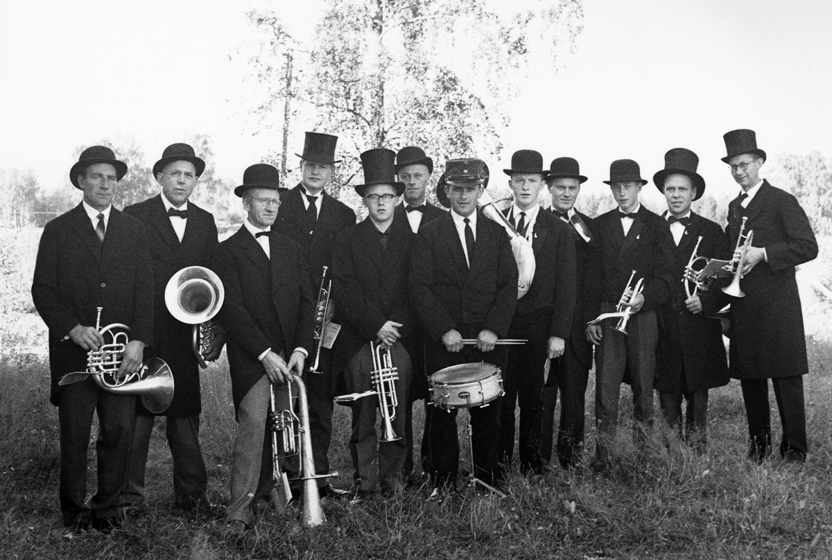 Furnes Musikkforening 1963. Under ett Røde kors arrangement reiste de rundt i bygda med lastebil og spilte musikk fra århundreskiftet i gamle kostymer.. Bildet er tatt på Bjørkhol i Furnes av Per Solheim.  F. v. Mikael Saglien,  Mikkel M. Dobloug, Arne Godager, Erik Dobloug, Ole Jesnes, Johannes Engstad, Kåre Åsvestad, Erik Larsen, Ole Dalseng, Lars Lund, Magne Dalen og Reidar Bækkelund. 