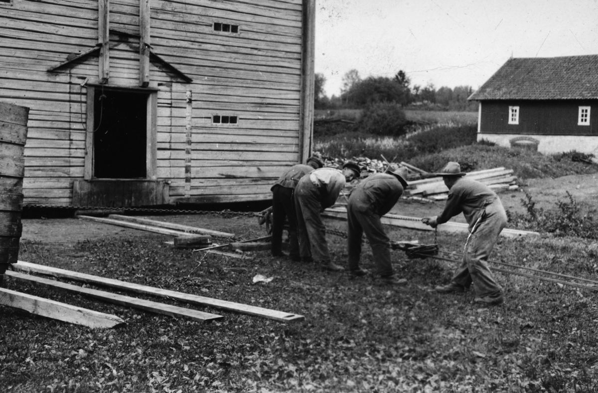 Flytting av låven på Nashaug hos Ole Nashaug. F. v: Edvard Ålerud og Andreas Jørgensen. De andre to er ukjente. 
