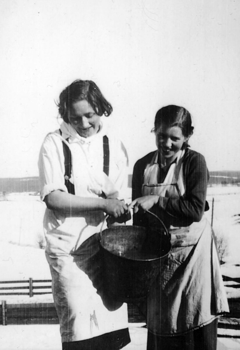 Gunhild Dahl og Ingrid Bryhni med skulebøtta, matavfall, ca. 1930. 