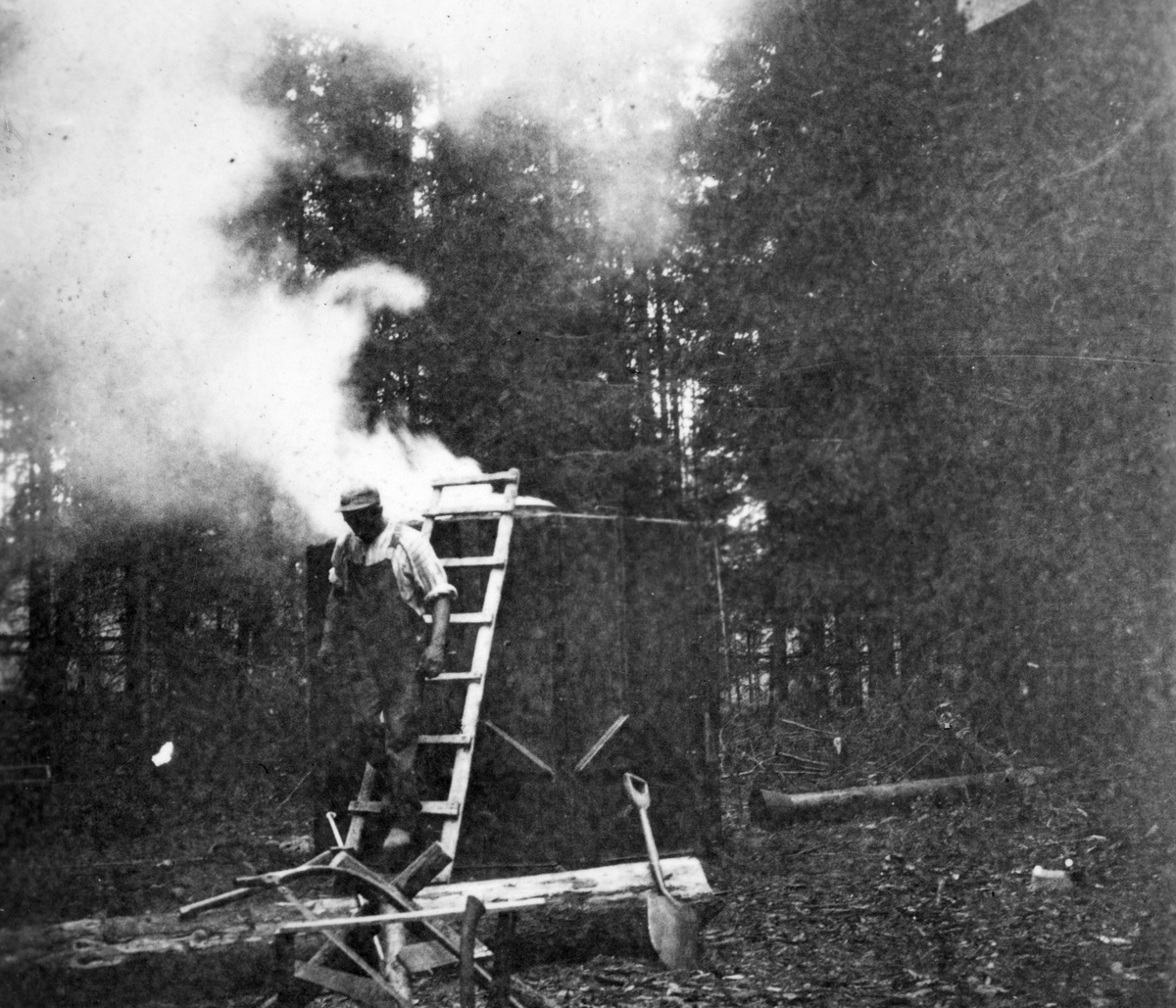 Oskar Bruun brenner tjære i Prestmarka i Stange på slutten av 1920-tallet. Tjærebrenning. 