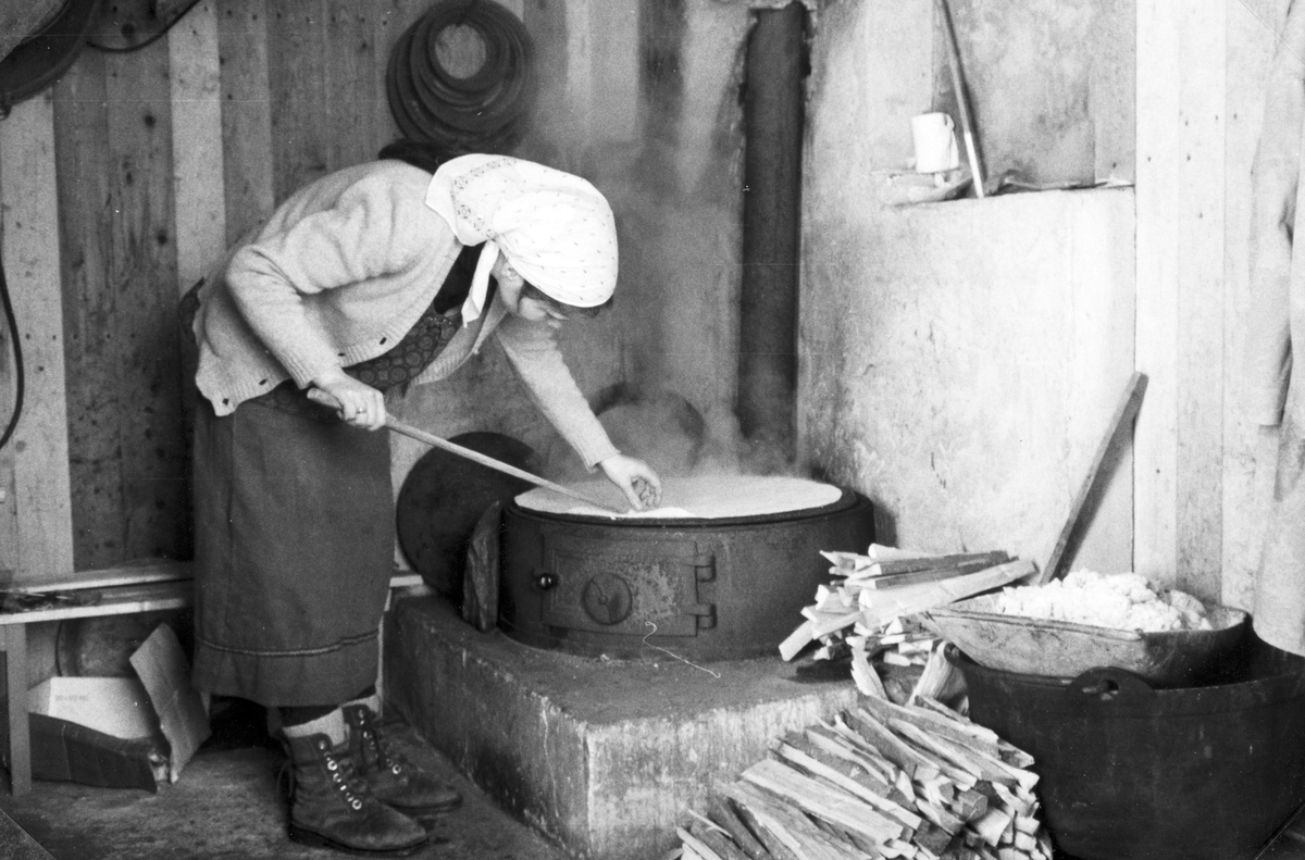 Lefsebaking i størhuset i Fossengen nordre, Vallset i desember 1978.  Eli Rønningsbakken steker lefse på takke. (Registrert av Oddmund Rønningsbakken)