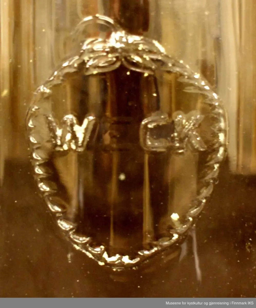 På siden av glasskrukken er Weck-selskapets logo stemplet/påtrykt i glassgodset. Logoen er et jordbær. Inni båret står det "WECK".