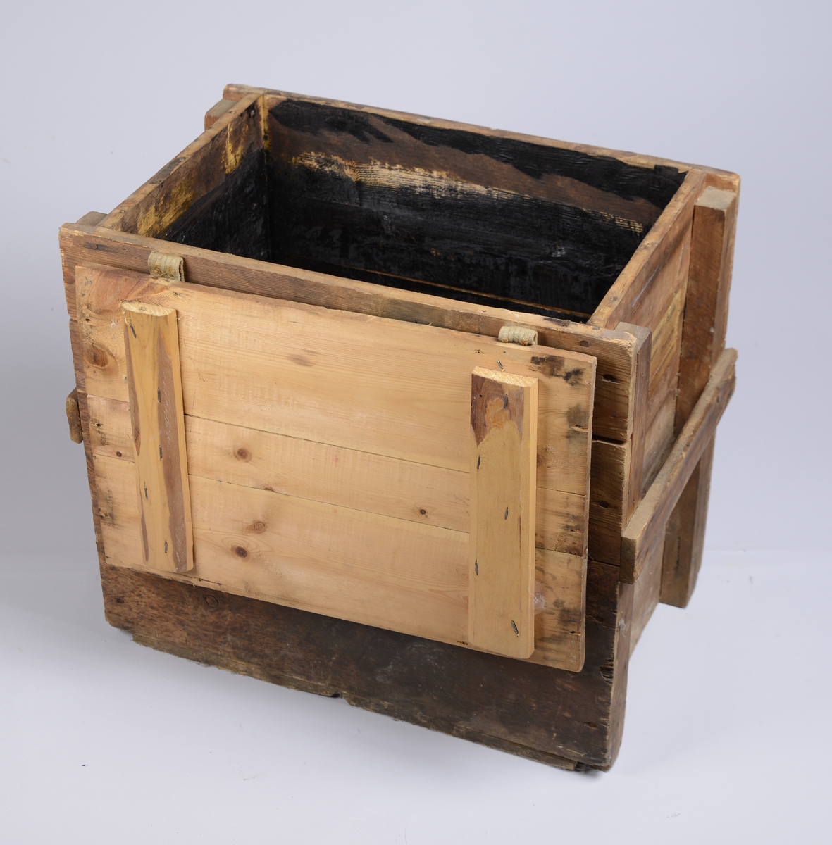 Trekasse av plank av forskjellige størrelser, med hengslet lokk. Kassen har informasjon påmalt på hver side. På kortsidene er det satt på en list som fungerer som håndtak.