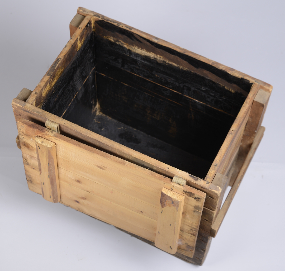 Trekasse av plank av forskjellige størrelser, med hengslet lokk. Kassen har informasjon påmalt på hver side. På kortsidene er det satt på en list som fungerer som håndtak.