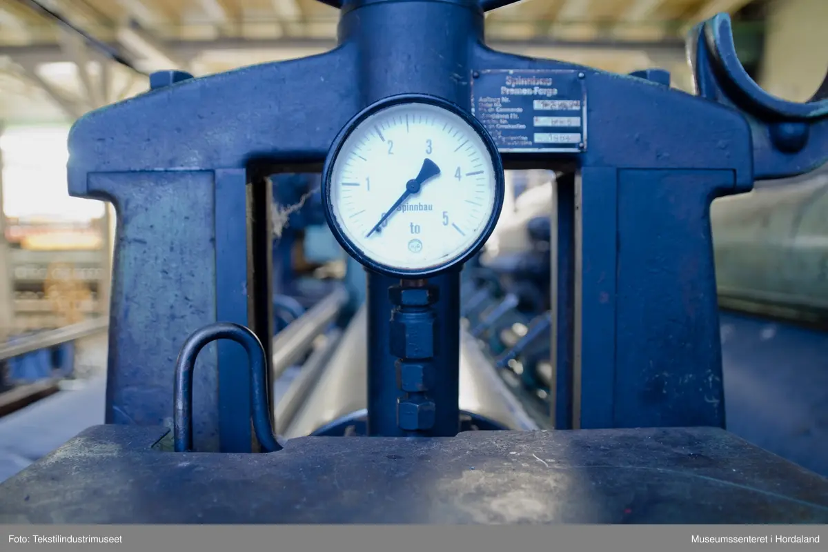 Kardeverk med tre kardemaskiner som er kopla saman og arbeider i serie, frå Oscar Schimmel & Co i Chemnitz, Tyskland. Frå ullinntaket i eine enden av maskina, blir ulla ført over valsar med metallkardar på, som fjernar ureinheiter og løyser opp floker i ullfibra. Ulla blir karda ein gong før den går over eit transportband i tre, blir snudd og karda to gonger til før det karda ullfloret går gjennom ein flordelar som deler det opp i remser. Remsene blir rulla opp på store metallspolar, og blir då kalla forgarn. I forgarnet ligg alle ullfibra etter kvarandre, men garnet er utan styrke og må spinnast for å bli til brukbart garn. 

Maskina var i bruk på Salhus Tricotagefabrik (1859-1989), og hadde her internt maskinnummer 5. Kardeverket står i hesteskoform med ullinntaket og ei kardemaskin på ei sida, to kardemaskiner og flordelaren på andre sida, og eit transportband i tre som bindeledd mellom dei to. Kardeverket blir drive av tre elektriske motorar som er festa til golvet på innsida av 'hesteskoen'. Maskina er grønmåla, med mange dekorative tannhjul med bua eiker, typisk for maskiner frå rundt 1900.

Det har seinare blitt montert ein støvsugar på kardeverket, som syg opp støv ved flordelaren, og transporterer det tilbake til ullinntaket. Røyra til støvsugaren ser 'heimelaga' ut, og er sett saman med bl.a. teip og ulike typar røyr.