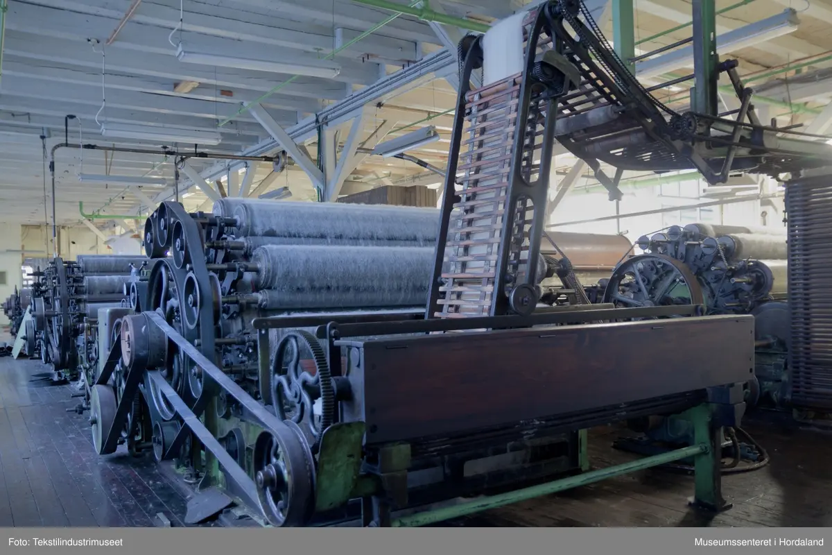 Kardeverk med tre kardemaskiner som er kopla saman og arbeider i serie, frå Oscar Schimmel & Co i Chemnitz, Tyskland. Frå ullinntaket i eine enden av maskina, blir ulla ført over valsar med metallkardar på, som fjernar ureinheiter og løyser opp floker i ullfibra. Ulla blir karda ein gong før den går over eit transportband i tre, blir snudd og karda to gonger til før det karda ullfloret går gjennom ein flordelar som deler det opp i remser. Remsene blir rulla opp på store metallspolar, og blir då kalla forgarn. I forgarnet ligg alle ullfibra etter kvarandre, men garnet er utan styrke og må spinnast for å bli til brukbart garn. 

Maskina var i bruk på Salhus Tricotagefabrik (1859-1989), og hadde her internt maskinnummer 5. Kardeverket står i hesteskoform med ullinntaket og ei kardemaskin på ei sida, to kardemaskiner og flordelaren på andre sida, og eit transportband i tre som bindeledd mellom dei to. Kardeverket blir drive av tre elektriske motorar som er festa til golvet på innsida av 'hesteskoen'. Maskina er grønmåla, med mange dekorative tannhjul med bua eiker, typisk for maskiner frå rundt 1900.

Det har seinare blitt montert ein støvsugar på kardeverket, som syg opp støv ved flordelaren, og transporterer det tilbake til ullinntaket. Røyra til støvsugaren ser 'heimelaga' ut, og er sett saman med bl.a. teip og ulike typar røyr.