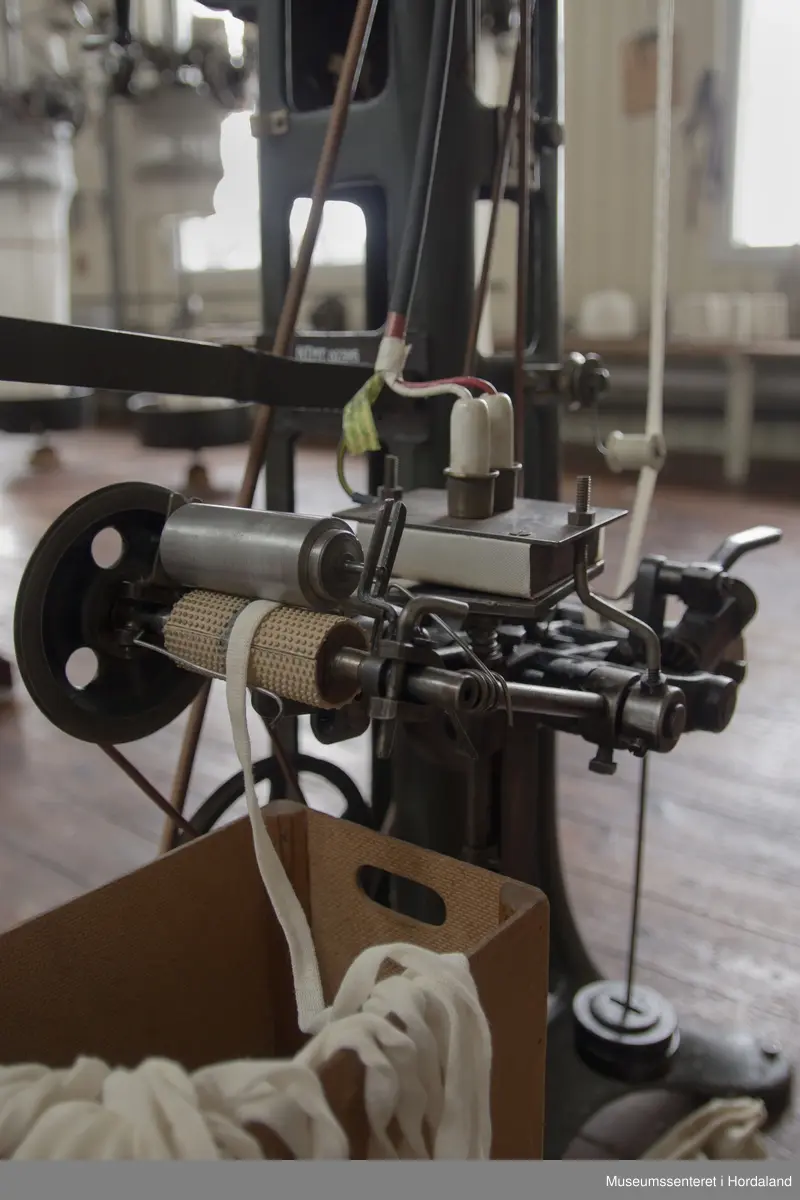 Rundstrikkemaskin med liten diameter frå Schubert & Saltzer Maschinenfabrik i Chemnitz i Tyskland, brukt på Salhus Tricotagefabrik utanfor Bergen. Maskina har berre 16 nåler, to trådar og ein trådførar, og vart truleg brukt til å strikke stay-band som gjorde saumane fastare.

Den har eit handtak på eine sida som ein kan bruke til å sveive maskina manuelt, og eit hjul på denne sida det maskina er kopla til reimdrifta i taket. Maskina har eit lite strykejern som stryk den ferdigstrikka "pølsa" etter kvart som den vert strikka. Strykefunksjonen er kopla til med elektrisk stikkontakt. Er dette ei forbetring som har komme i ettertid? Det kan òg tenkjast at det har vore ei rulle festa til maskina som rulla opp bandet direkte.