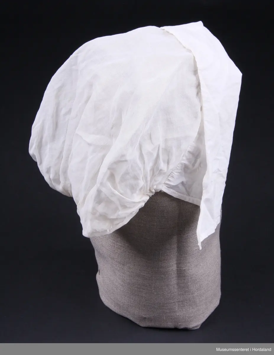 Svært tynt bomullslerret og brem i litt tjukkare lerret ( men framleis tynt - batist).
Strikk bak i nakken. Sølve hua er i eit stykke, medan bremmen har saum midt oppe på hovudet.Smal maskinsydd fall på bremmen.