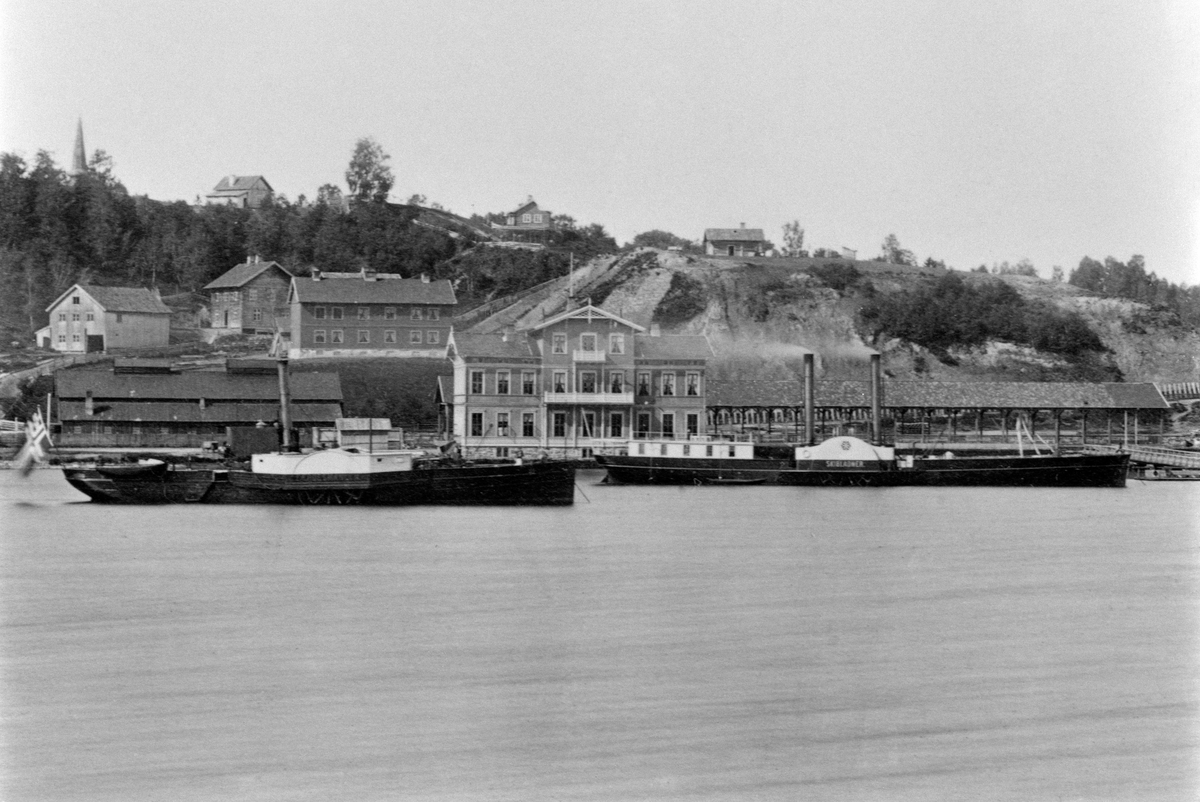 Eidsvoll, Jernbanebrygga, Eidsvoll stasjon, Mjøsbåtene D/S Færdesmanden til venstre og D/S Skibladner til høyre ved Eidsvoll damskipsbrygge. I bakgrunnen spiret på Eidsvoll kirke.