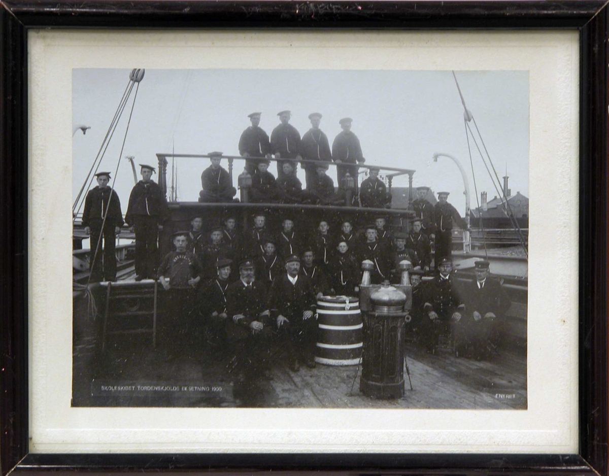 Gruppebildet av besetningen, menn og gutter, på Skoleskipet Tordenskjold stående bak natthuset på dekk året 1900.