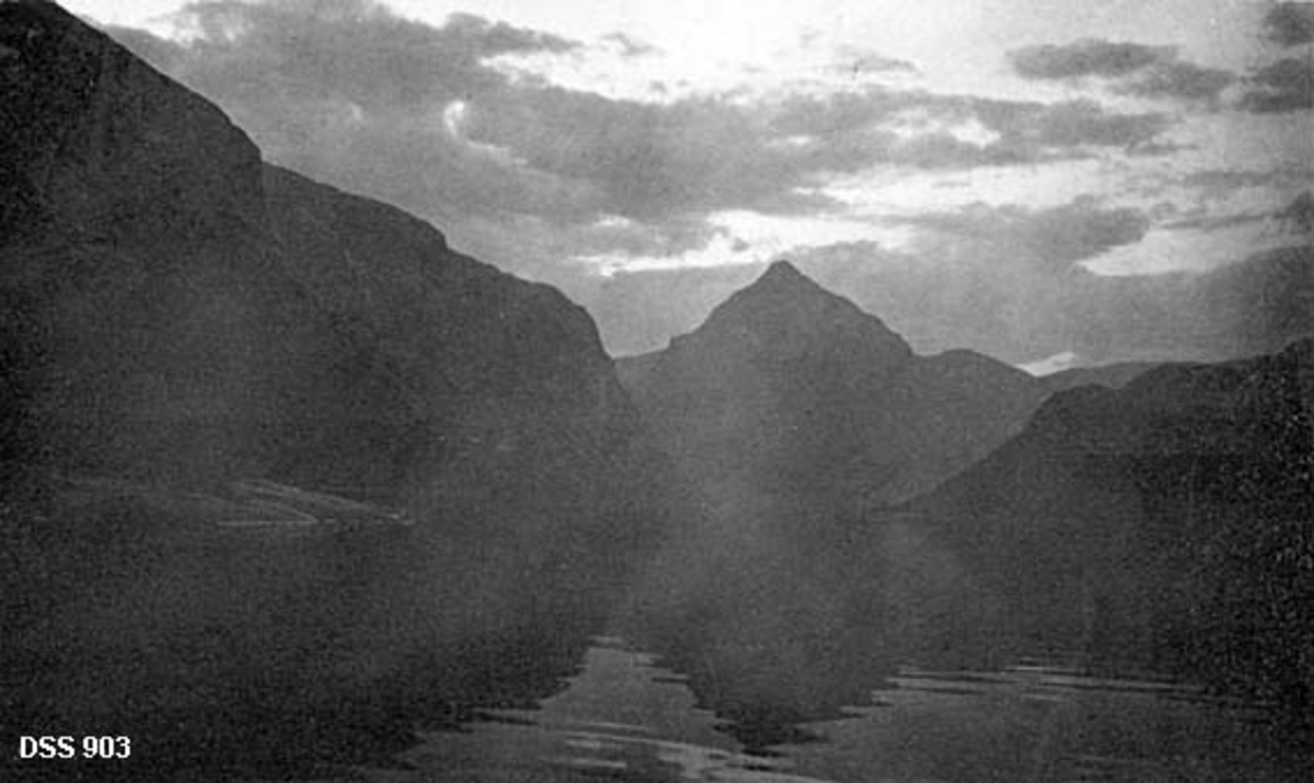 Landskap ved Storvatnet i Steigen.  Fotografiet viser vatnet med omliggende til dels bratte fjellrygger.  Om lag midt i bildet kneiser Storvasstind med sin spisse topp mot en delvis skyet midnattsolhimmel. 